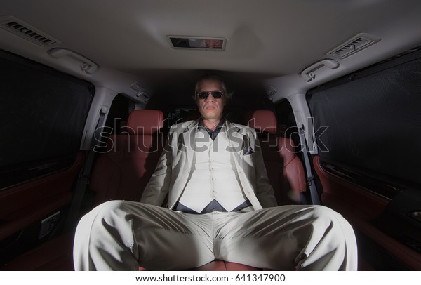 Gentleman, rich man\
in a white suit in the\
car