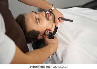 Gentleman Tilted Back In Barber Chair During A Beard Trim