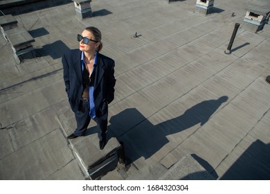 gentlewoman, glamorous portrait of a woman in a man's suit in sunglasses on the roof over the city on a clear day - Shutterstock ID 1684320304