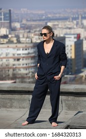 gentlewoman, glamorous portrait of a woman in a man's suit in sunglasses on the roof over the city on a clear day - Shutterstock ID 1684320313