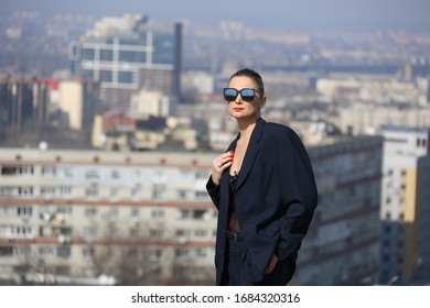 gentlewoman, glamorous portrait of a woman in a man's suit in sunglasses on the roof over the city on a clear day - Shutterstock ID 1684320316