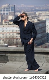 gentlewoman, glamorous portrait of a woman in a man's suit in sunglasses on the roof over the city on a clear day - Shutterstock ID 1684320322