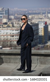 gentlewoman, glamorous portrait of a woman in a man's suit in sunglasses on the roof over the city on a clear day - Shutterstock ID 1684320331