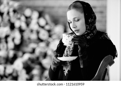 Gentlewoman sitting with cap of tea outdoors at winter - Shutterstock ID 1121610959