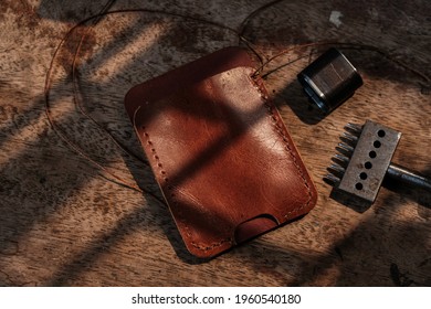 Genuine leather card holder wallet with tool on wood background craftmanship working