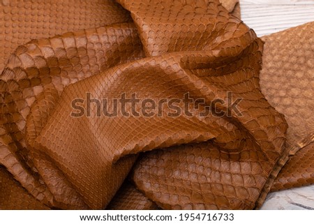 Genuine python leather dyed in light-brown folded on a wooden table