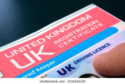 Genuine UK registration certificate for a purchased car and UK Driving Licence on top. Registration document also known as a vehicle log book V5C. Stafford, United Kingdom, January 30, 2022.