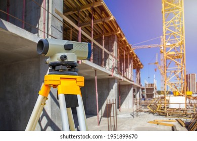 Geodesy. Theodolite At A Construction Site. Surveyor Secured The Level To A Tripod. Construction Crane Near The House. Concept - Geodetic Surveys. Concept - Work As A Surveyor. Topography.