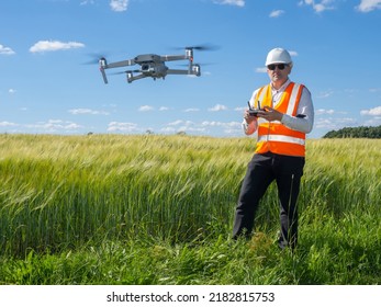 Geodetic technologies. Man surveyor next to green field. Geodetic survey with help of drone. Surveyor reflective vest. Topographic survey of area from drone. Drone for surveyor purposes