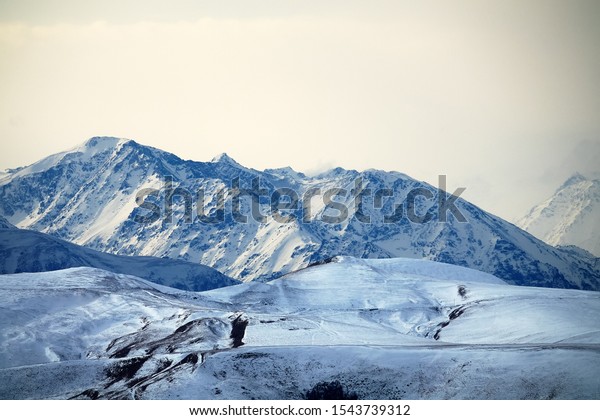 Geography and Geology. Typical view of piedmont
(foothill belt; submountain region) of large mountain system. View
of Greater Caucasus Mountain Range with snowfields, glaciers.
Asia-Europe border