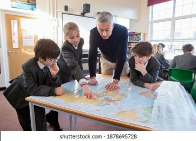 Geography teacher and middle school students using a map in the classroom. - Powered by Shutterstock