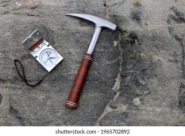 Geologists compass on the stones with hammer. Geology science concept. The geologist's hammer and tools are laid out on a stone while filedwork