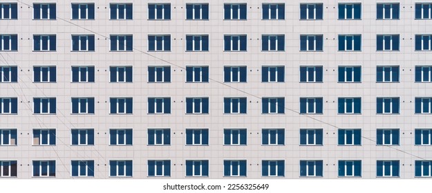 Geometric backdrop with lots of window rows. Simple classic design high-rise building. Realistic concept of office building. Apartment house texture background. Many windows on big wall close-up.