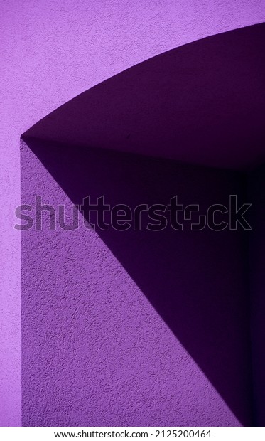 geometric black and purple shapes of shadow on\
exterior cement or concrete wall of building in afternoon light\
dividing black lines separating image into triangular shapes\
vertical format framed\
space