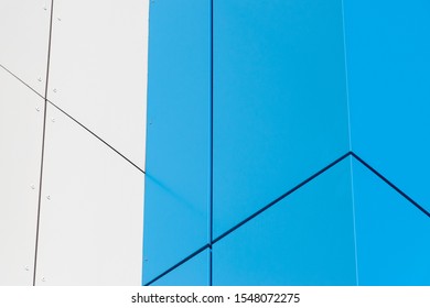 Geometric colored building facade elements with planes, lines and corners with light flare and reflections for an abstract background and texture of white, blue, gray colors. Place for text