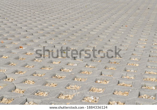 geometric concrete tile with\
holes. Covering for car parking. the holes are filled with small\
stones