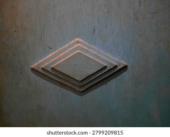 A geometric design featuring three concentric diamond shapes is affixed to a wooden surface