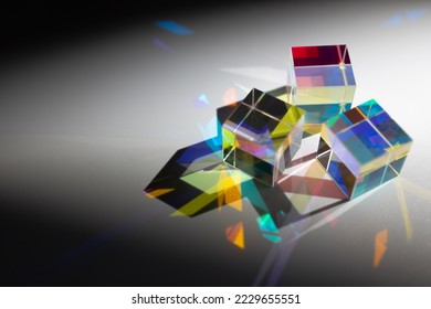 Geometric figure prisms with light diffraction of spectrum and hard shadow on white background