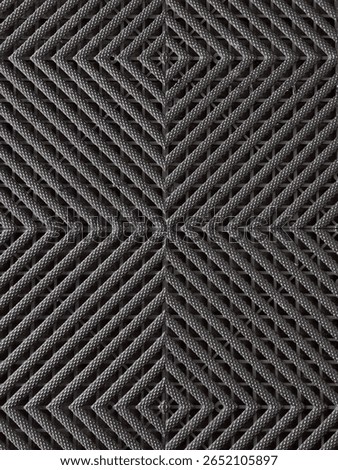 Geometric Grey Interlocking Grid Pattern. A close-up, top-down view of a dark grey, possibly rubber or plastic, interlocking grid surface.