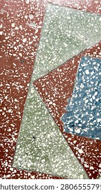 Geometric multicolor terrazzo texture background with triangle pattern. Vertical full frame photo of mosaic flooring with terracotta red, green and blue polygonal sections, vintage architectural abstract backdrop.