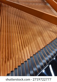 Geometric pattern created by the parallel copper bass strings inside a grand piano stretching diagonally across the frame