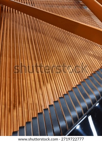 Geometric pattern created by the parallel copper bass strings inside a grand piano stretching diagonally across the frame