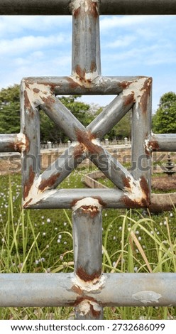 Geometric pattern of a rusty square and cross metal fence