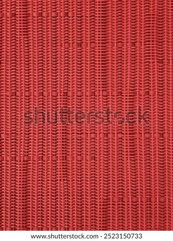 Geometric pattern of woven red plastic strands. Ideal for backgrounds, textures, or design elements in projects with a modern or industrial aesthetic.