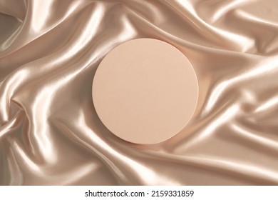 Geometric platform podium on pastel wave silk satin fabric background. Blank minimal cylinder form mock up background for beauty cosmetic product presentation. Top view, copy space