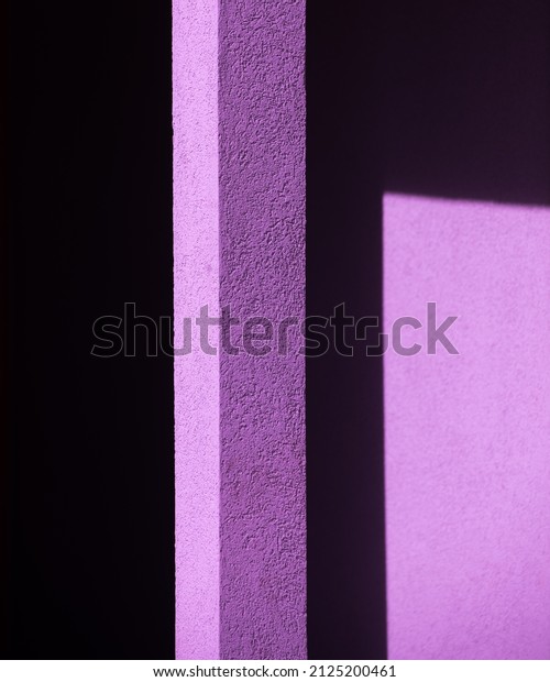 geometric purple shapes from black shadows on exterior\
cement or concrete wall of building in afternoon light dividing\
black lines separating image into triangular shapes vertical format\
framed space 