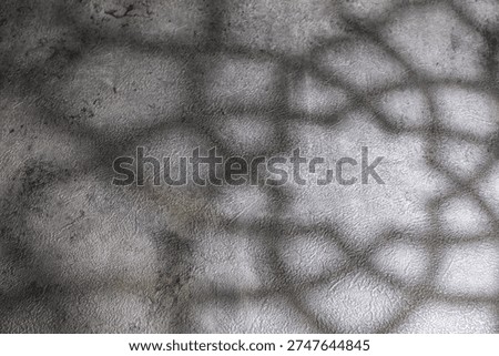 A geometric window-like shadow pattern appears across a gray textured wall surface. The shapes are softly defined and spread evenly with moderate contrast. Suitable for seasonal backgrounds.