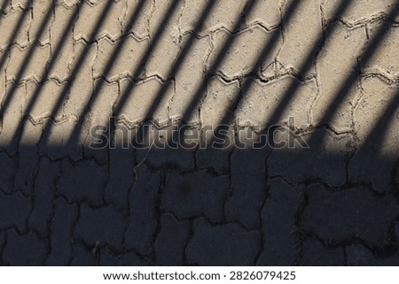 Geometrical Shadow Pattern: Ornate Gate Shadow on Asphalt
High-resolution photograph capturing the strong, high-contrast shadow cast by an intricate wrought-iron gate onto rough, dark asphalt pavement. The geometric lines and curves create a powerful abstract pattern. Perfect graphic element for backgrounds, urban designs, architectural visualizations, or overlay textures. Clear focus on the shadow detail.