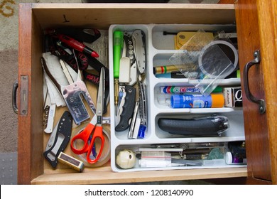 George, South Africa, 2018 10 21: Untidy Desk Drawer In Study Showing Knives, Writing Equipment, Left-handed Scissors And Electric Shaver