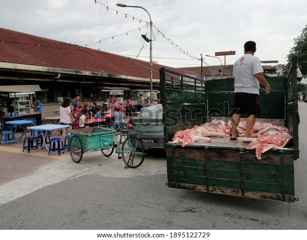George Town, Penang, Malaysia, December 15,\
2018: A man among carcasses is delivering meat to the Pulau Tikus\
Wet Market off the back of an old\
truck.