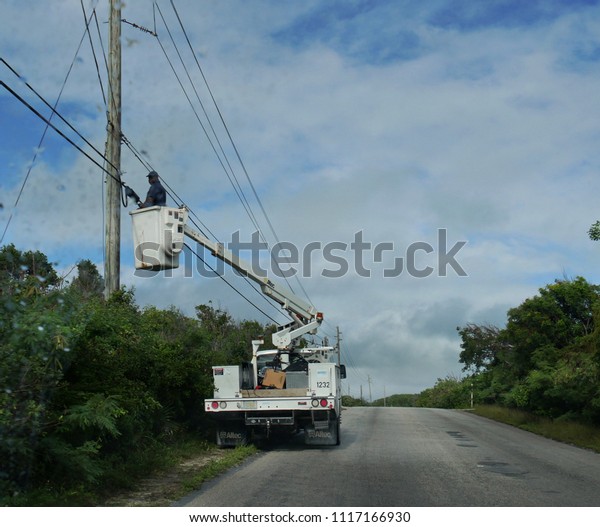 GEORGETOWN, BAHAMAS—JANUARY 2018: A\
lineman in a cable car repair electrical lines in Georgetown.\
