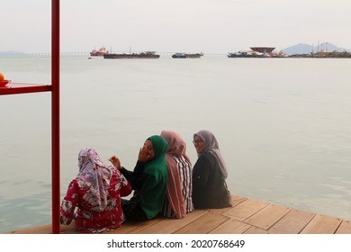 GEORGETOWN, MALAYSIA - Feb 02, 2020: Rear view four Asian women with moslem headscarf enjoying together the view on the Georgetown harbor by showing heart shapes with thier raised arms 