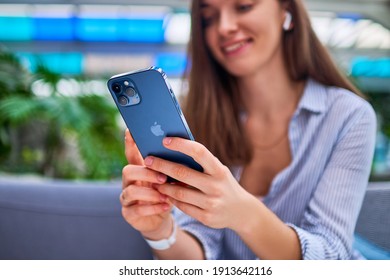 Georgia - January 19, 2021 - Modern casual smart millennial woman using newest Iphone 12 Pro Max for online browsing and virtual remotely chatting