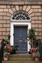 Georgian Grey Door, Entrance To House, With Two Trees In Plant Pots. Decorative Fanlight, Brass Hardware, Columns, Railings And Steps. Edinburgh Scotland