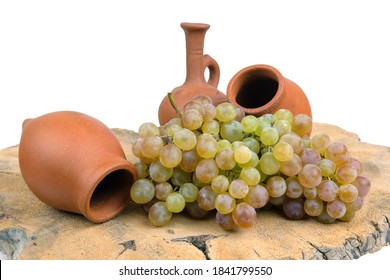 Georgian traditional decorative clay jugs for wine with grape on the wooden log slice with isolated background