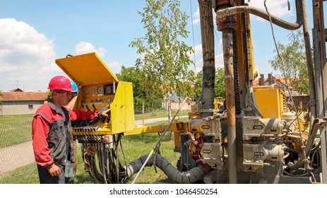 Geothermal Drilling Rig Equipment. Worker Operating Drilling Rig Control Panel. Drilling Geothermal Well For A Residential Geothermal Heat Pump. Workers On Drilling Rig. 