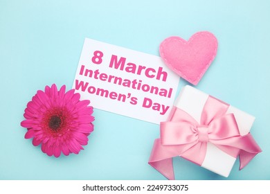 Gerbera flower, felt heart, gift box and card with text 8 March International Women's Day on blue background - Shutterstock ID 2249733075