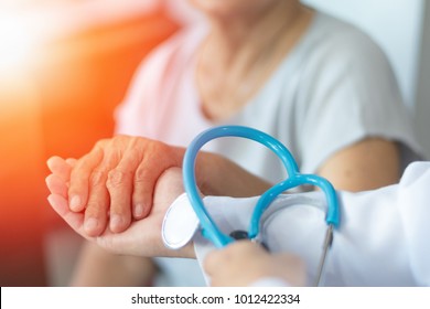 Geriatric Doctor Or Geriatrician Concept. 
Doctor Physician Hand On Happy Elderly Senior Patient To Comfort In Hospital Examination Room Or Hospice Nursing Home Or Wellbeing County.