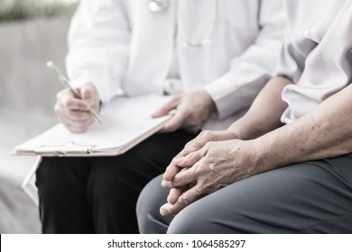 Geriatric Doctor Or Geriatrician Concept. 
Doctor Physician Writing On Patient Chart Diagnosis Depressed Elderly Senior Older In Hospital Or Hospice Nursing Home.