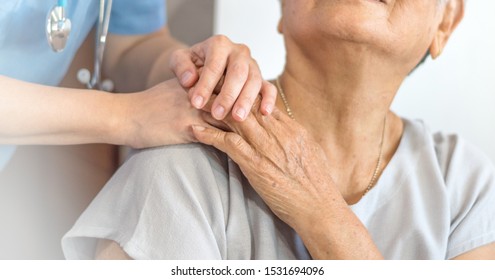 Geriatric doctor or geriatrician concept. Doctor physician hand on happy elderly senior patient to comfort in hospital examination room or hospice nursing home or wellbeing county. 