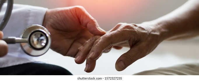 Geriatric Doctor Or Geriatrician Concept. Doctor Physician Hand On Happy Elderly Senior Patient To Comfort In Hospital Examination Room Or Hospice Nursing Home Or Wellbeing County. 