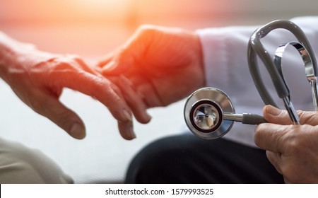 Geriatric Doctor Or Geriatrician Concept. Doctor Physician Hand On Happy Elderly Senior Patient To Comfort In Hospital Examination Room Or Hospice Nursing Home Or Wellbeing County. 