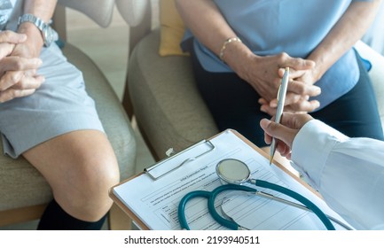 Geriatric Doctor Or Geriatrician Concept. Doctor Physician With Elderly Senior Patient Knee Problem In Hospital Examination Room Or Hospice Nursing Home Or Wellbeing County. 