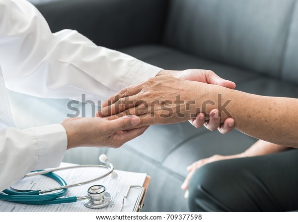 Geriatric doctor (geriatrician) consulting and
diagnostic examining elderly senior adult patient (older person) on
aging and mental health care in medical clinic office or hospital
examination room 