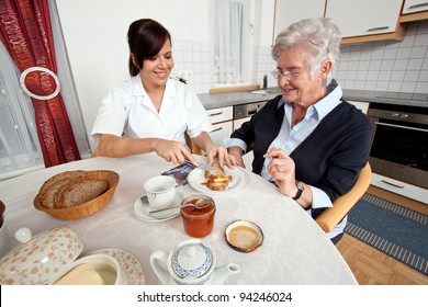 a geriatric nurse helps elderly woman at breakfast - Powered by Shutterstock