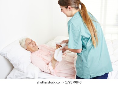 Geriatric nurse washing bedridden senior woman and drying her hands in nursing home - Powered by Shutterstock